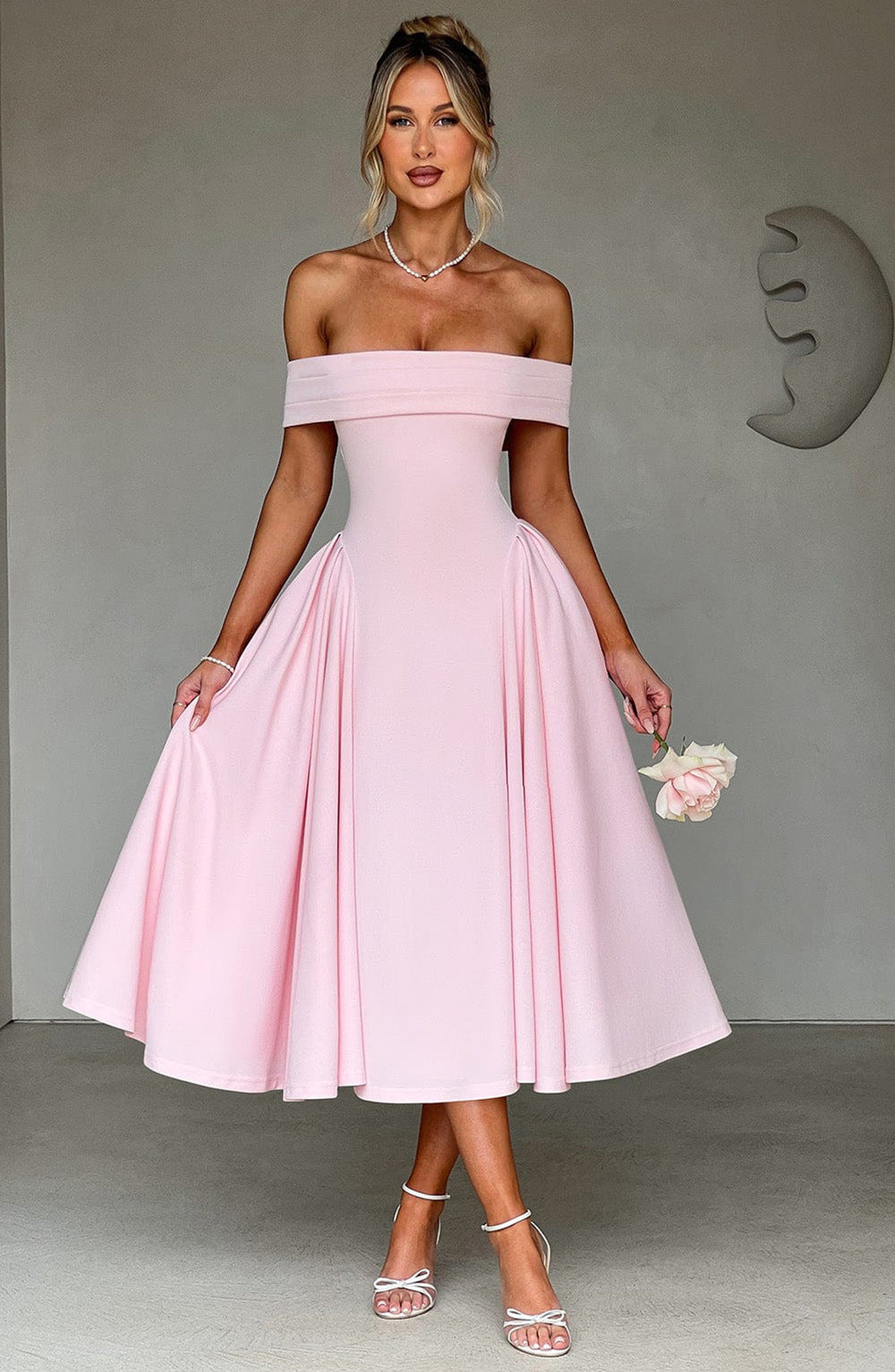 Woman showcasing an elegant midi dress with off-shoulder neckline and graceful fit.
