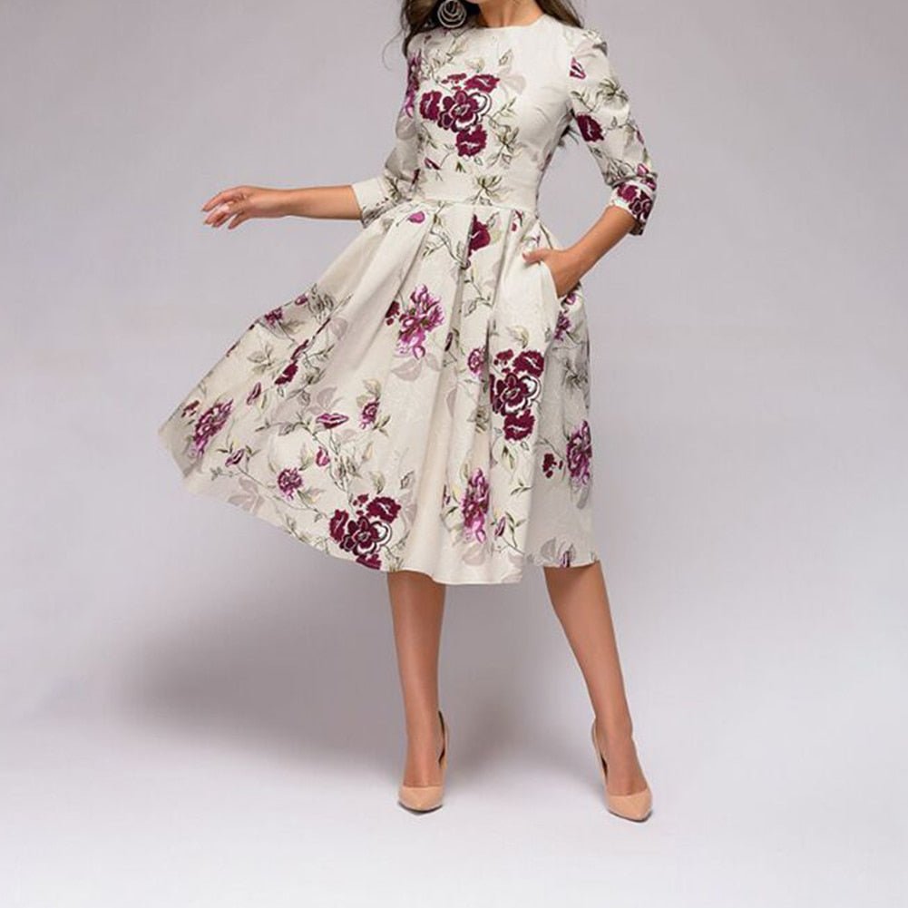 Woman wearing a floral A-line knee-length dress against a plain background.