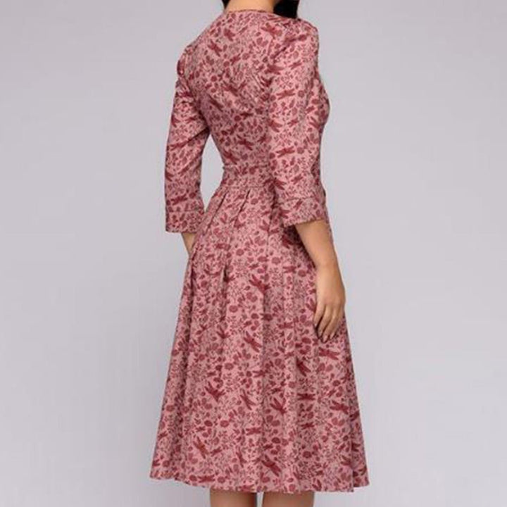 Female model in a floral print knee-length dress on a clean background, back view angle