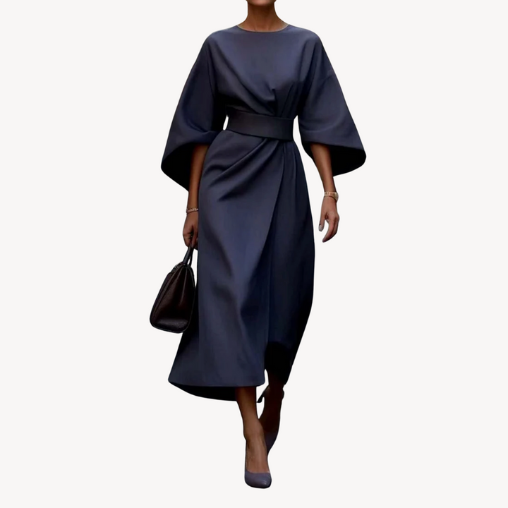 Female model posing in a belted A-line midi dress on a plain background.