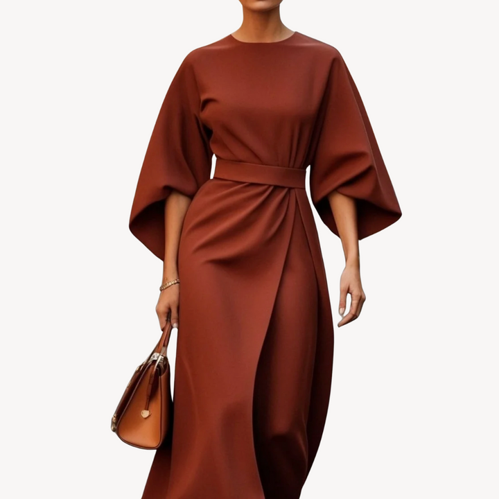 
Woman wearing a wide sleeve midi dress with a waist tie on a plain background.