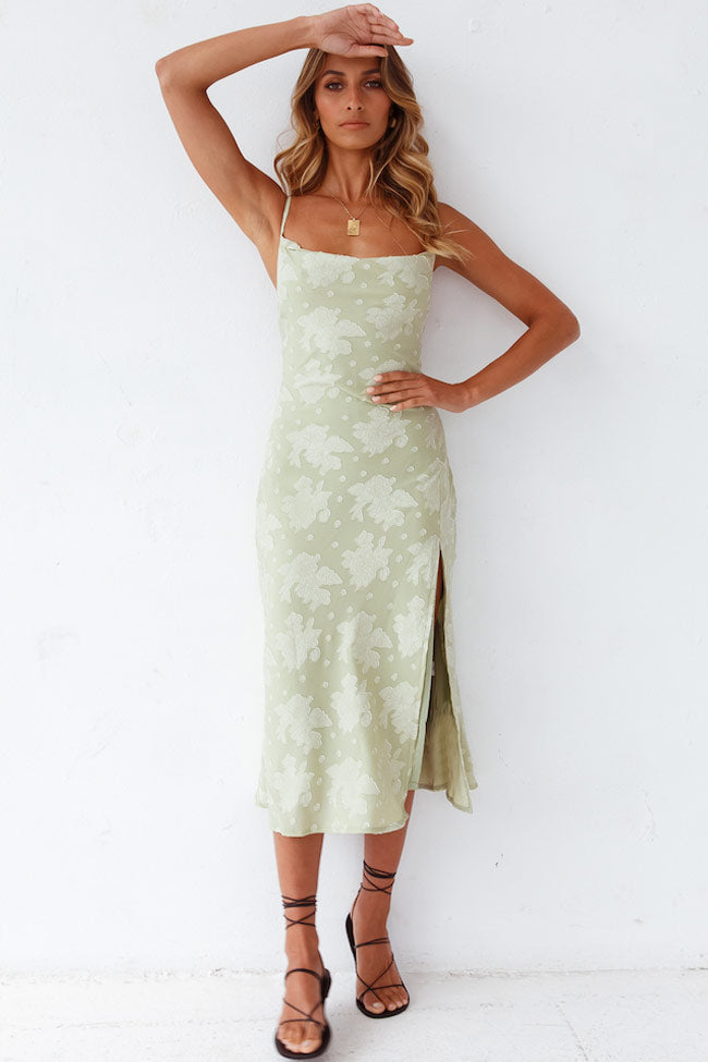 Model in a floral slip midi dress with cowl neckline and high slit against a clean background.