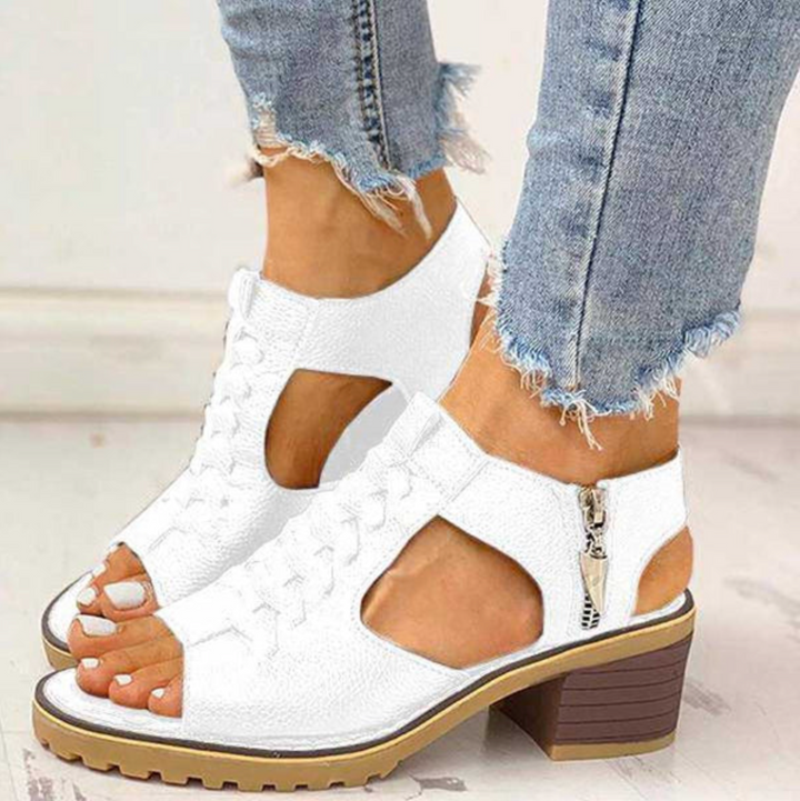 Elegant sandals with supportive heel presented with feet only on a plain background.