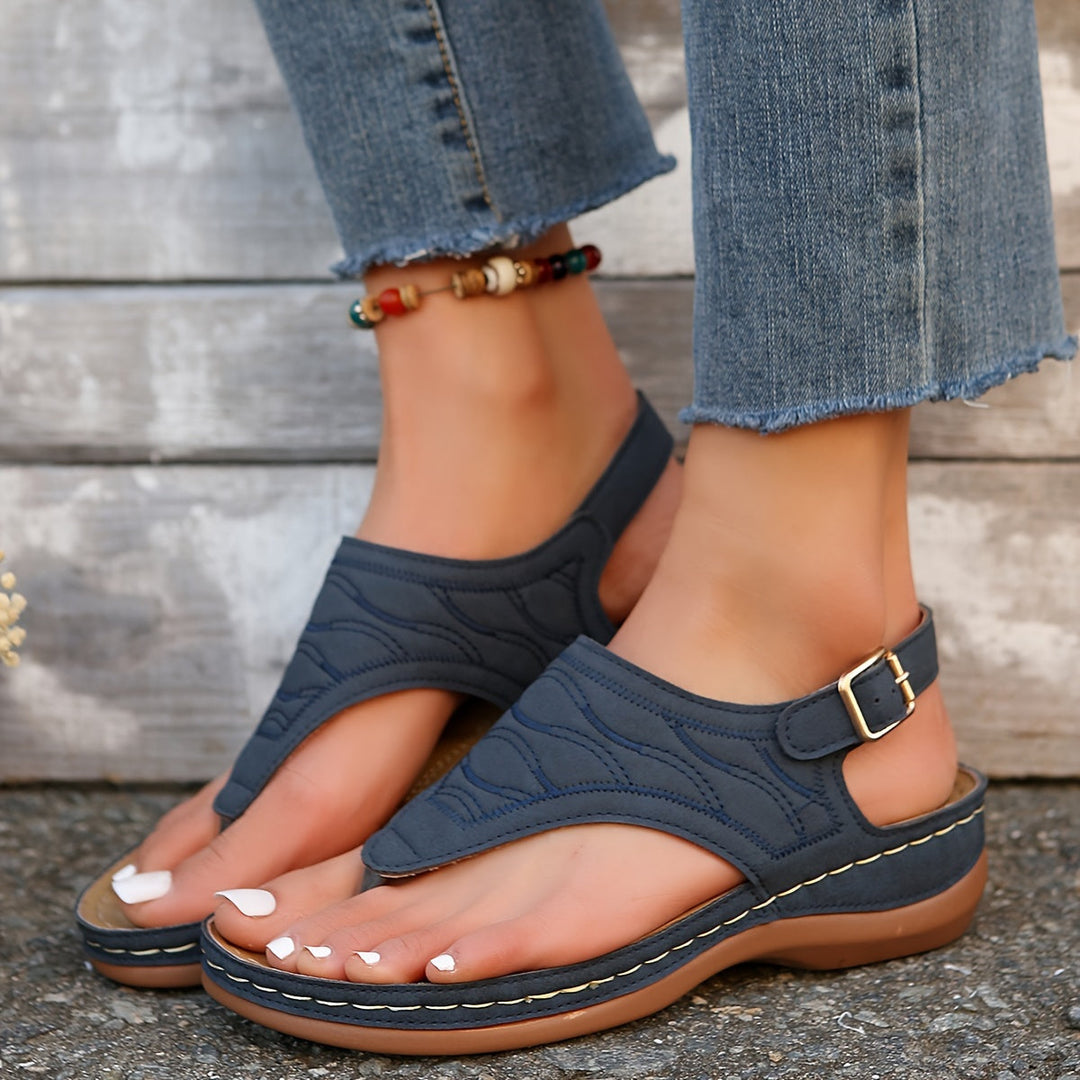 Woman wearing lightweight summer sandals with a plain studio background.