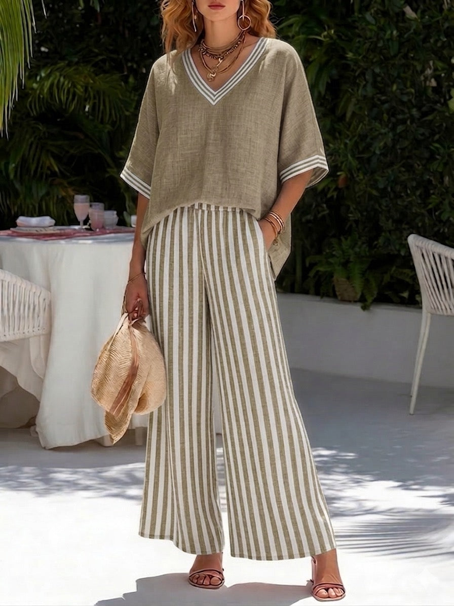 Female model wearing a striped V-neck top and wide leg pants set on a plain background.