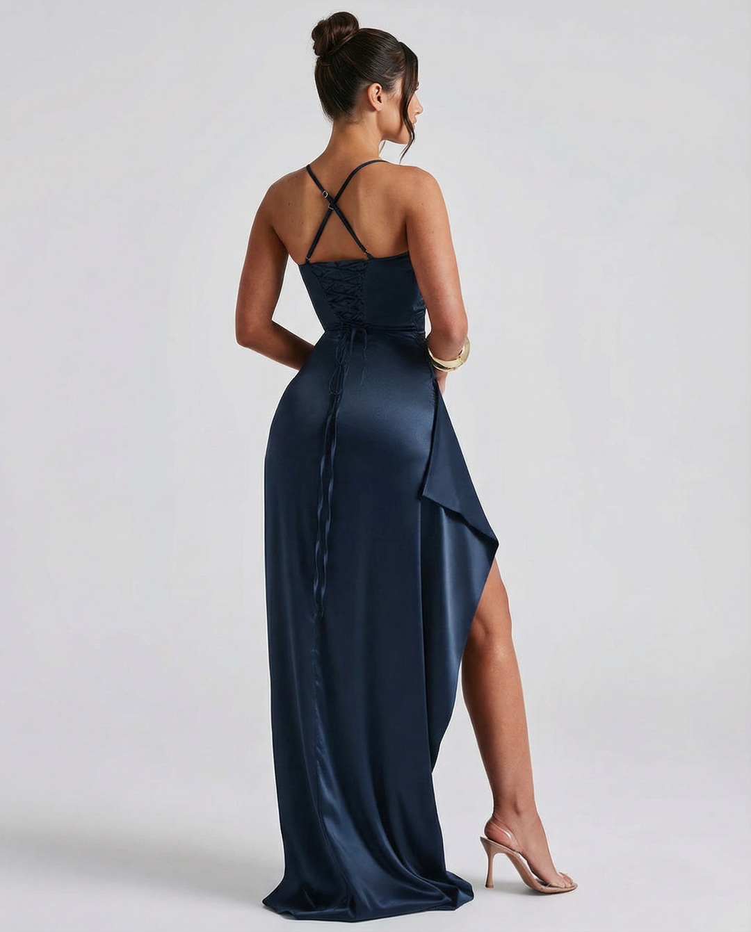 Model wearing a fitted navy maxi dress with cross-back straps on a plain background.