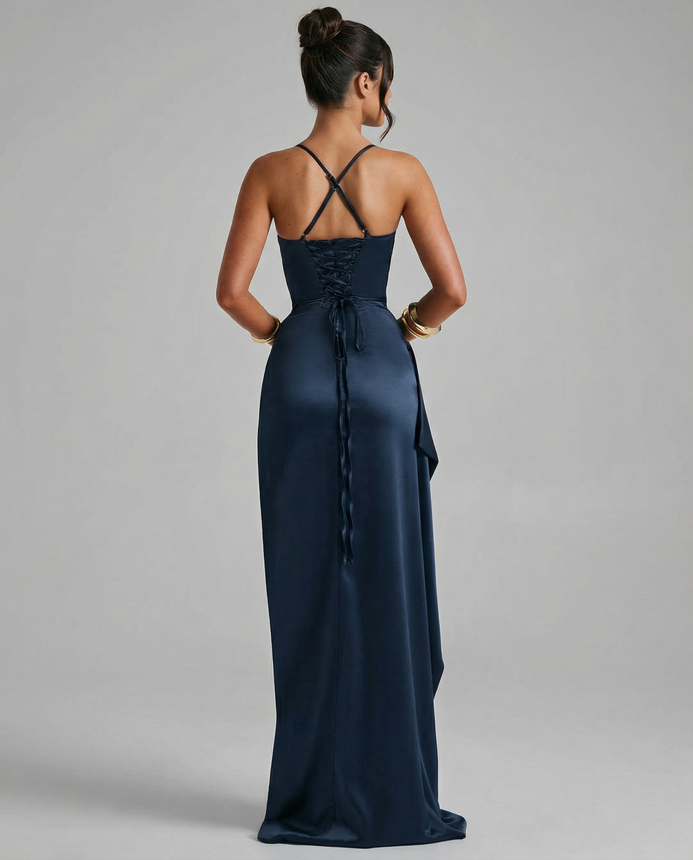 Woman in a navy long dress with lace-up back and thigh-high split on a plain background.