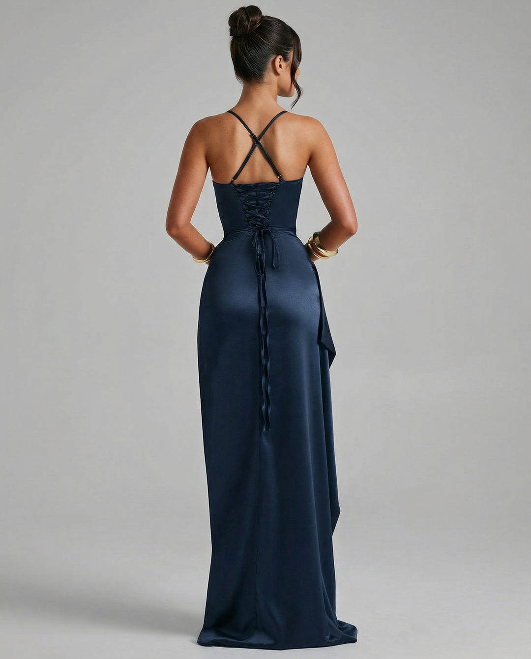 Woman in a navy long dress with lace-up back and thigh-high split on a plain background.