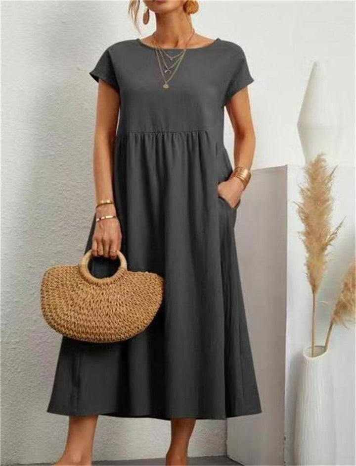  Female model posing in a long casual dress with a clean and simple design on a plain background.
