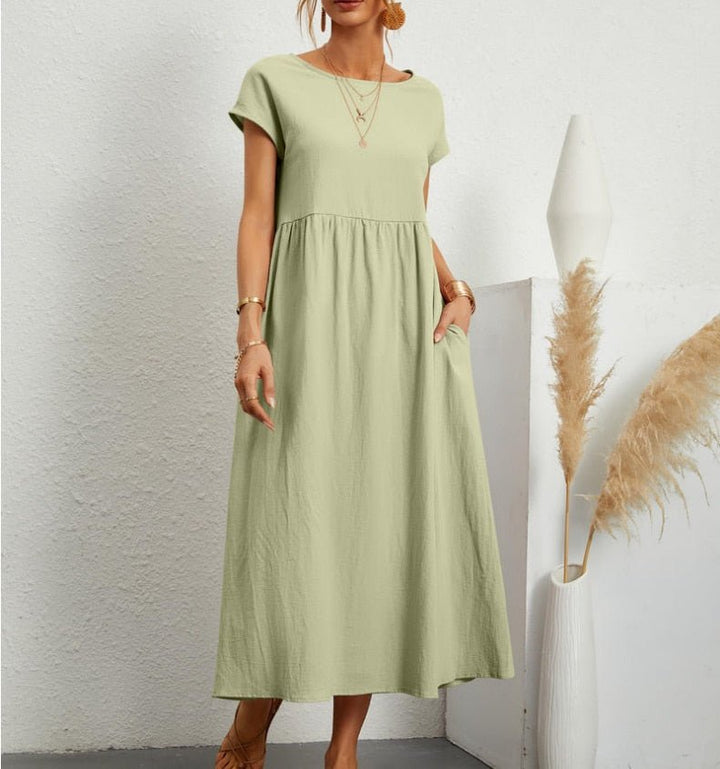  Female model posing in a versatile sleeveless dress on a plain background.