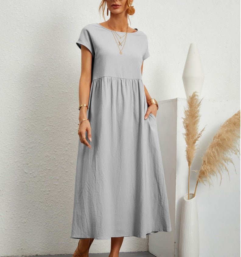  Woman showcasing a sleeveless maxi dress with a relaxed silhouette on a plain background.