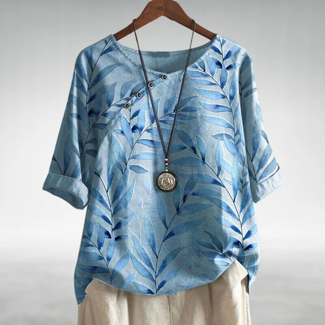 Chic women’s blouse displayed on a plain background with a soft flowing silhouette and refined feminine details.