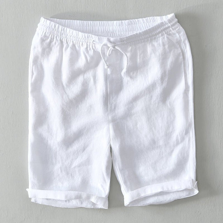  Male model showcasing casual Bermuda shorts with pocket details on a plain background.
