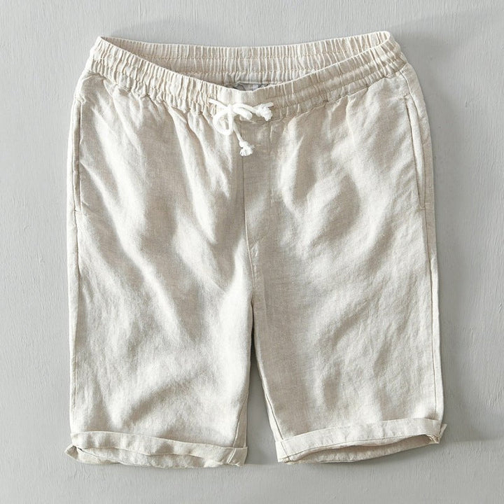 Male model standing in relaxed-fit summer shorts on a plain background.
