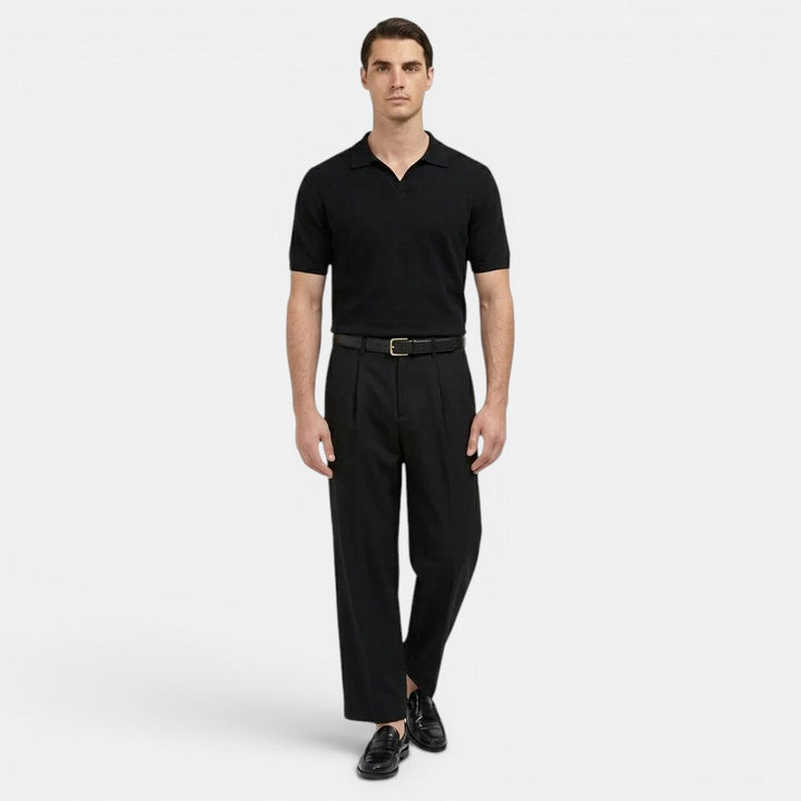  Male model styled in pleated trousers paired with a classic top on a plain background.