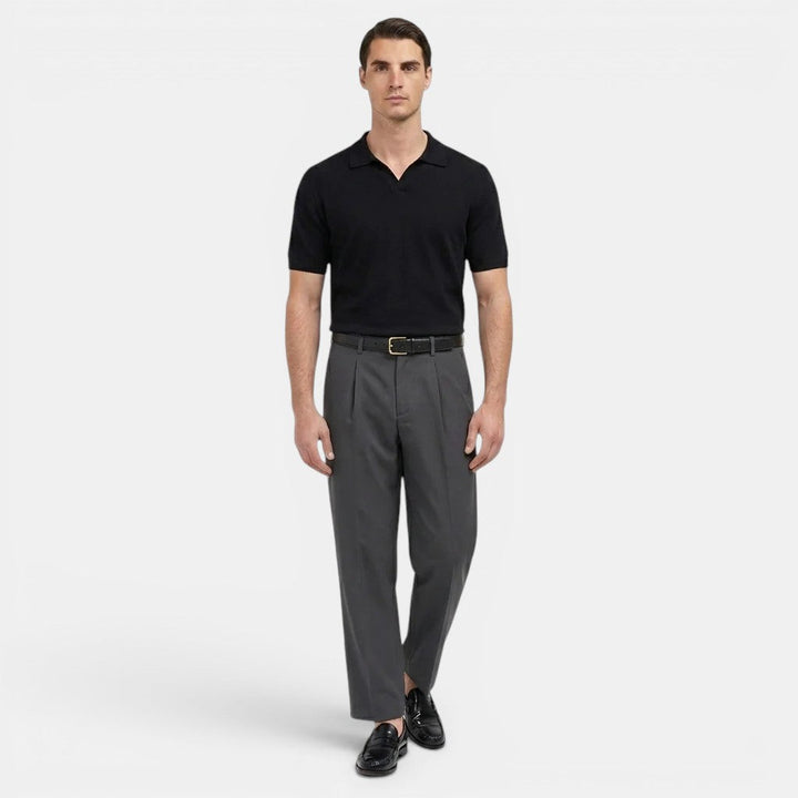  Male model displaying pleated front trousers with a refined look on a plain background.