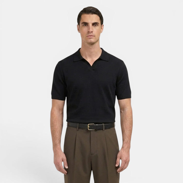 Male model posing in tailored pleated trousers with a structured fit on a plain background.
