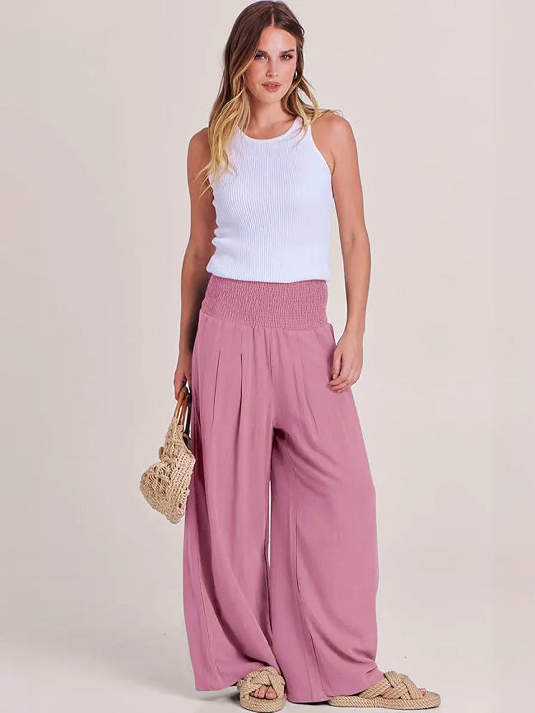 Women’s wide leg pants with smocked high waist on a plain background.