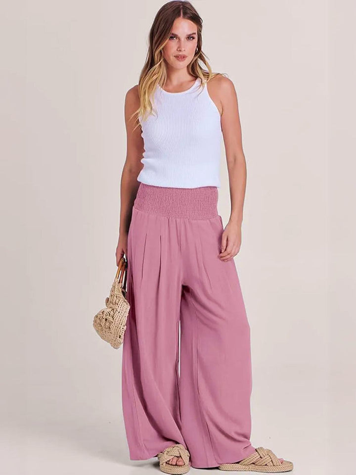 Women’s wide leg pants with smocked high waist on a plain background.