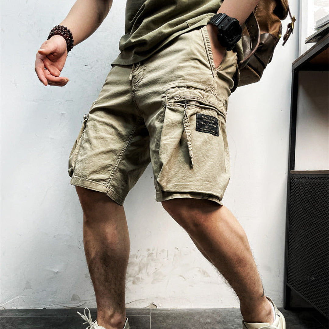 Model wearing men’s cargo shorts with drawstring waist and multiple pockets on a plain background.