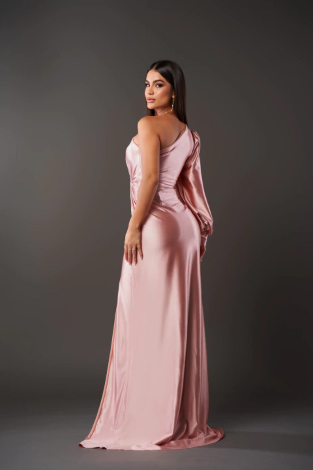 Woman wearing a sophisticated long dress with flowing fabric on a clean background.