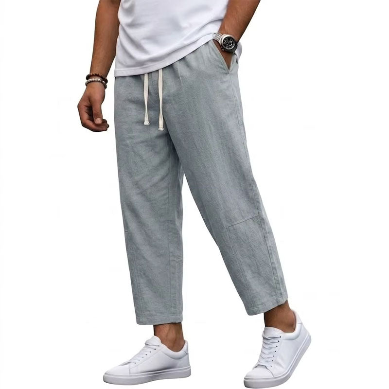 Male model in relaxed cropped pants with side pockets on a plain background.