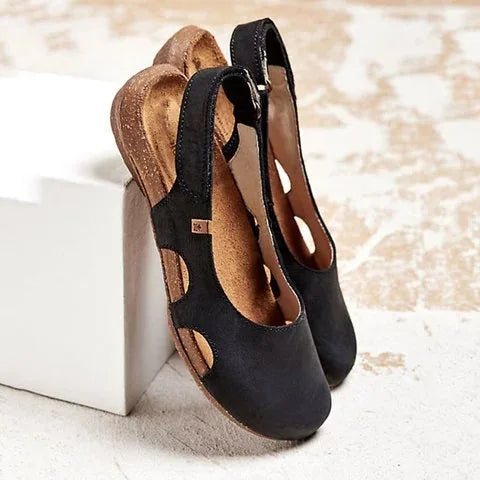 Woman wearing lightweight open sandals with back strap on a plain background.