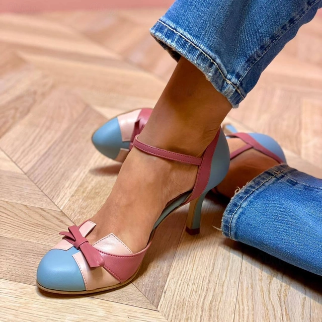 Foot wearing elegant stiletto sandal on a plain background.