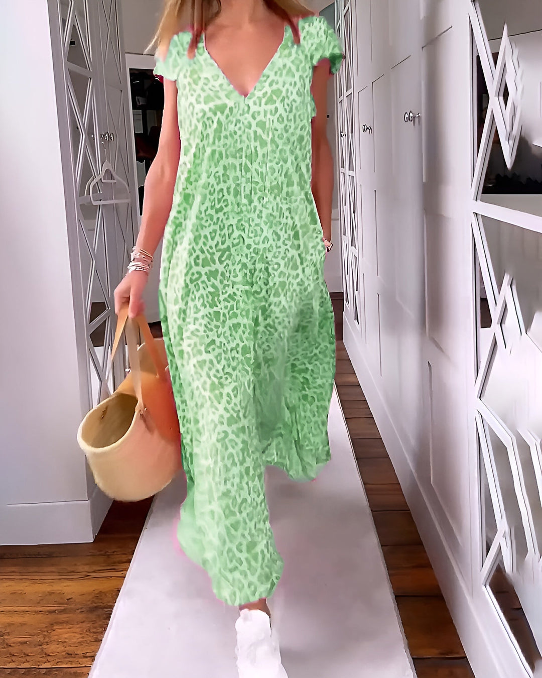 Woman modeling a long V-neck animal print dress on a clean plain background.