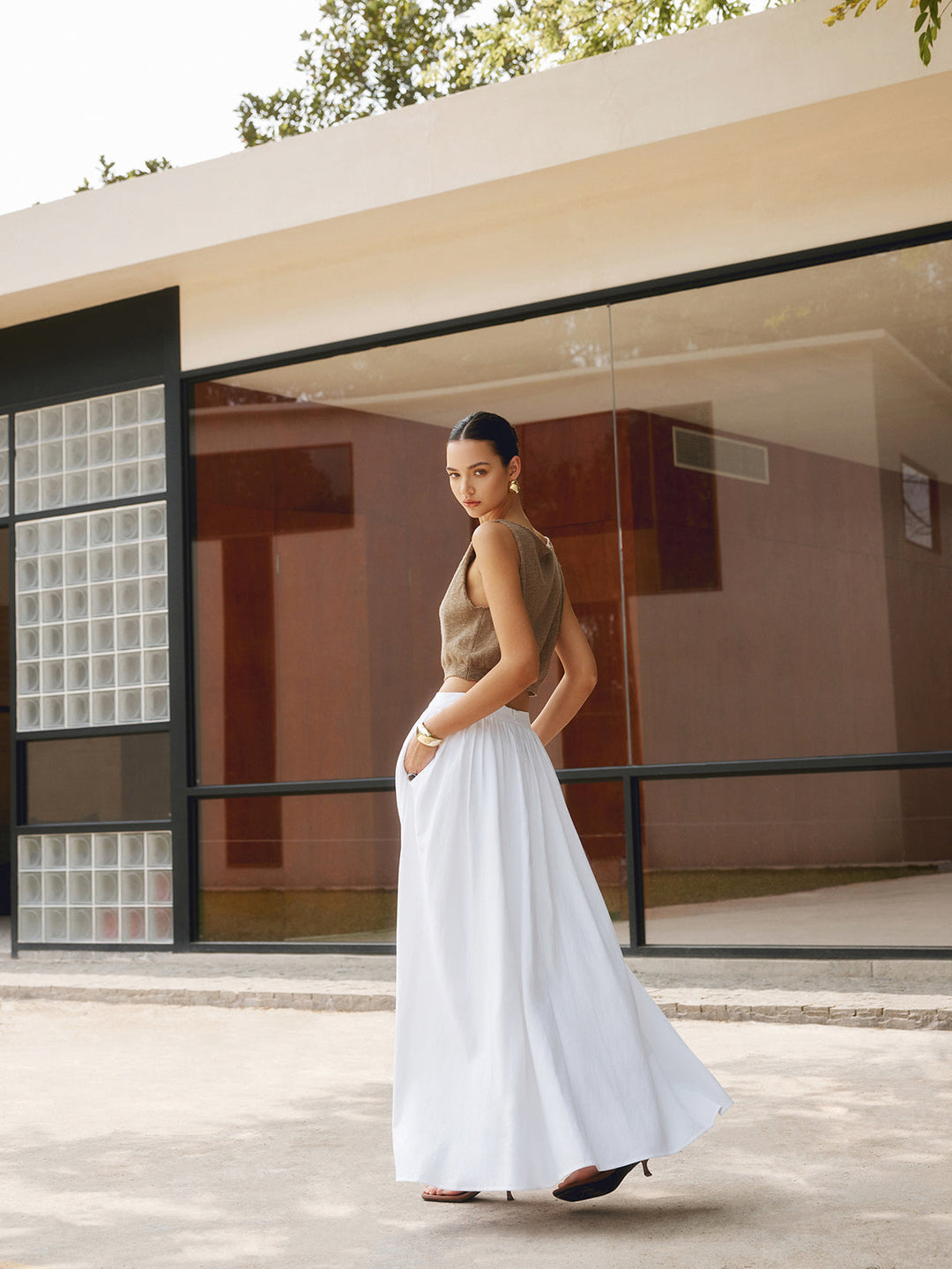 High waist maxi skirt with soft pleats and a graceful flowing shape on plain background.