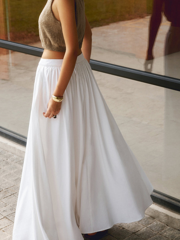 Flowing long skirt with waist pleats and elegant movement against a plain background.