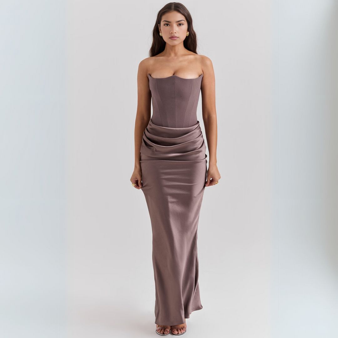 Woman styled in a satin strapless maxi dress with structured corset waist and draped hip accent.