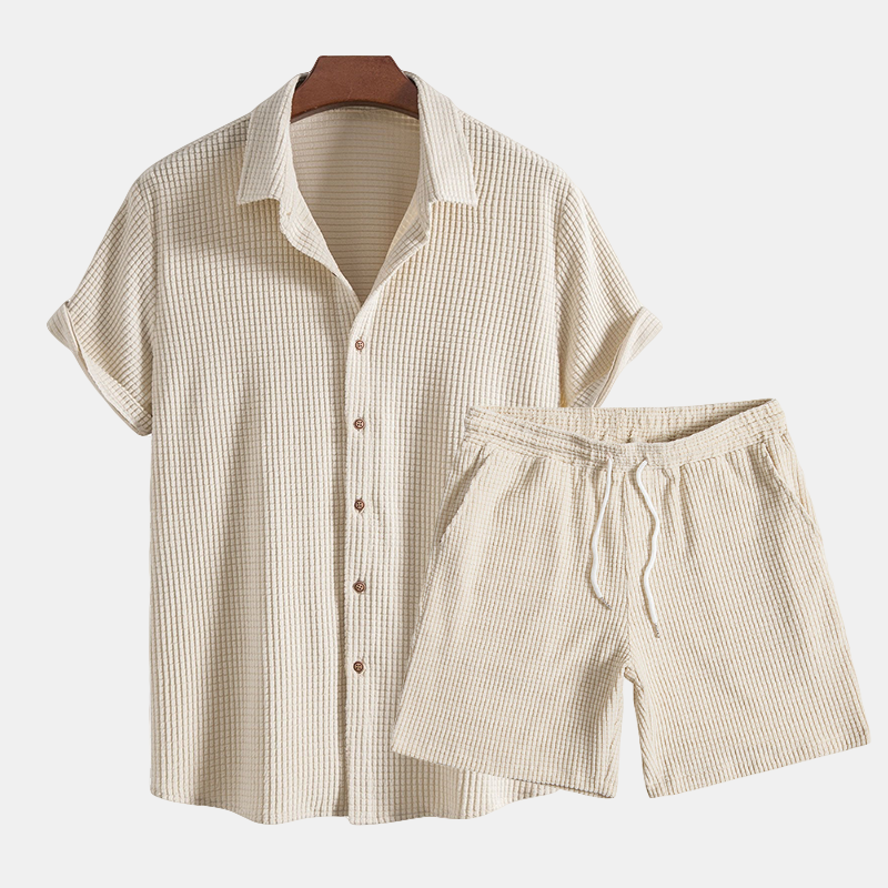 A short sleeve button-up shirt and drawstring shorts set against a plain background.