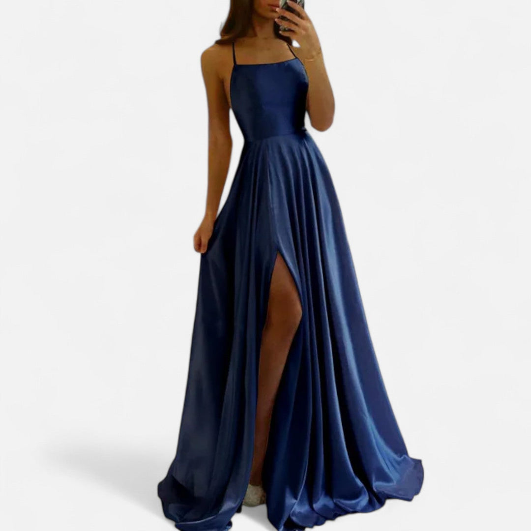 Female model side angle in long dress on plain white.
