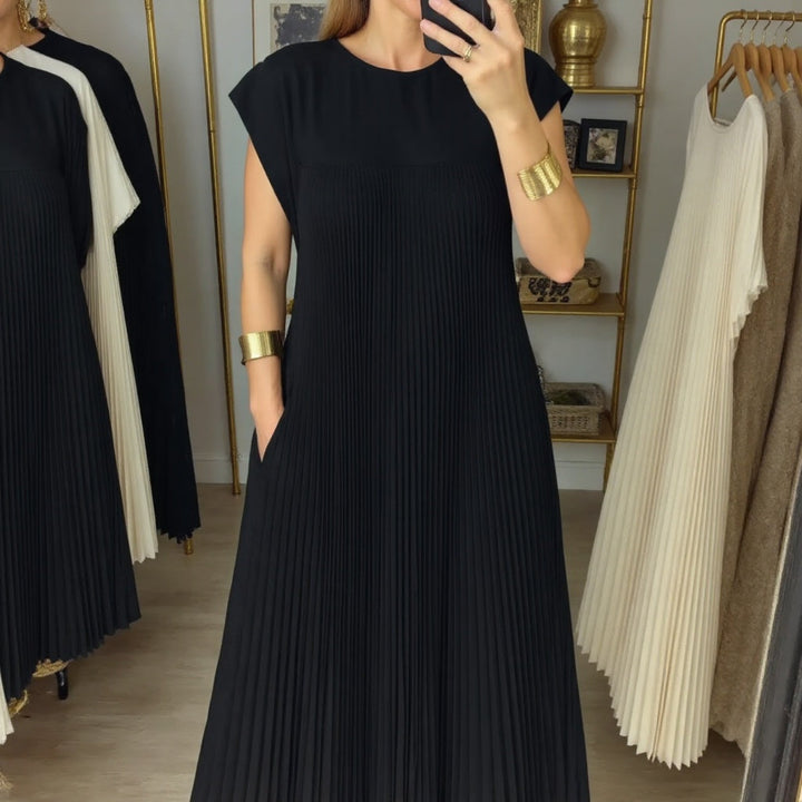 Female model posing in a long flowing dress with soft pleats.