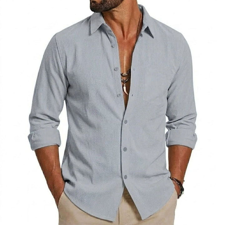 Male model wearing a navy long-sleeve button-down shirt with white contrast detailing against a plain background.