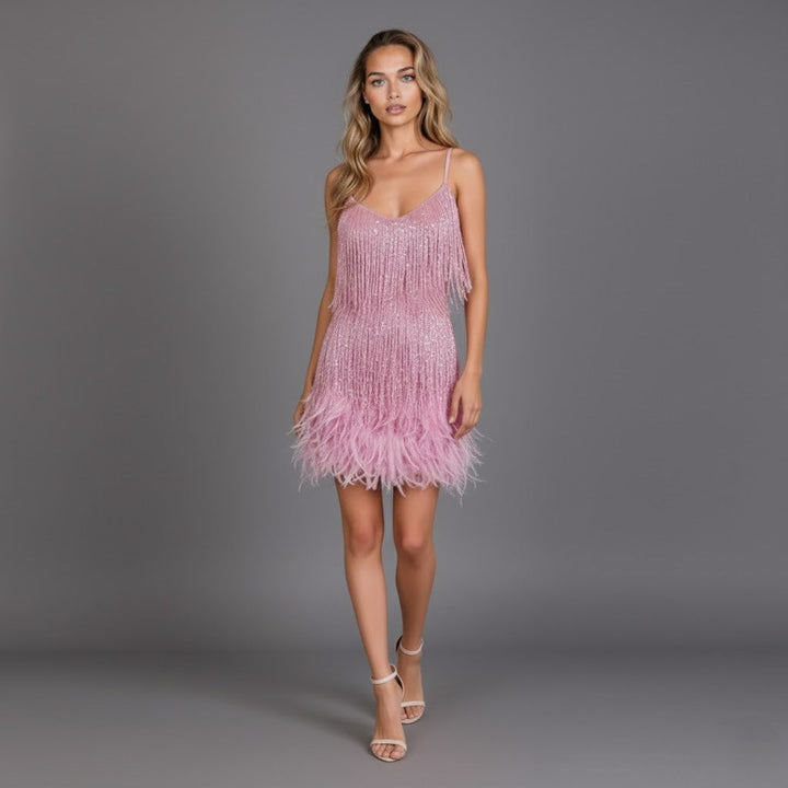 Female model wearing a strappy fringe feather dress on a plain background.