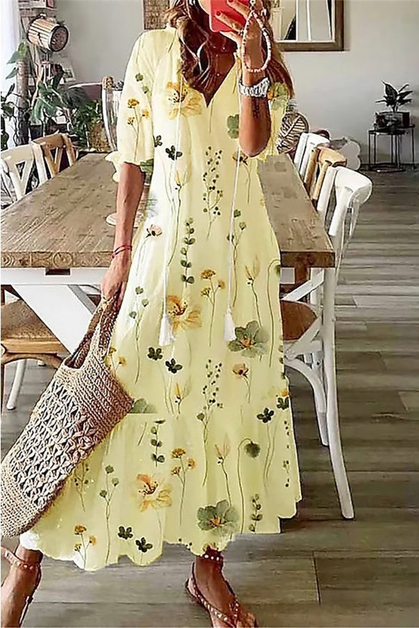 Woman in a watercolor floral maxi dress with relaxed sleeves on a plain background.