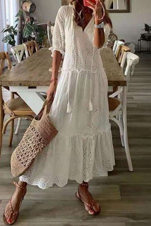 Woman styled in a botanical print maxi dress with soft flowing silhouette on a plain background