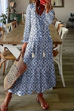 Female wearing a long floral dress with ruffled hem in a plain studio setting.
