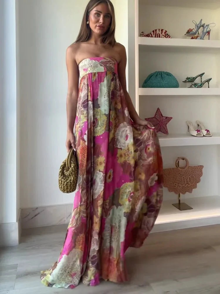  Woman in a pink floral maxi dress with a flowing silhouette on a plain background.