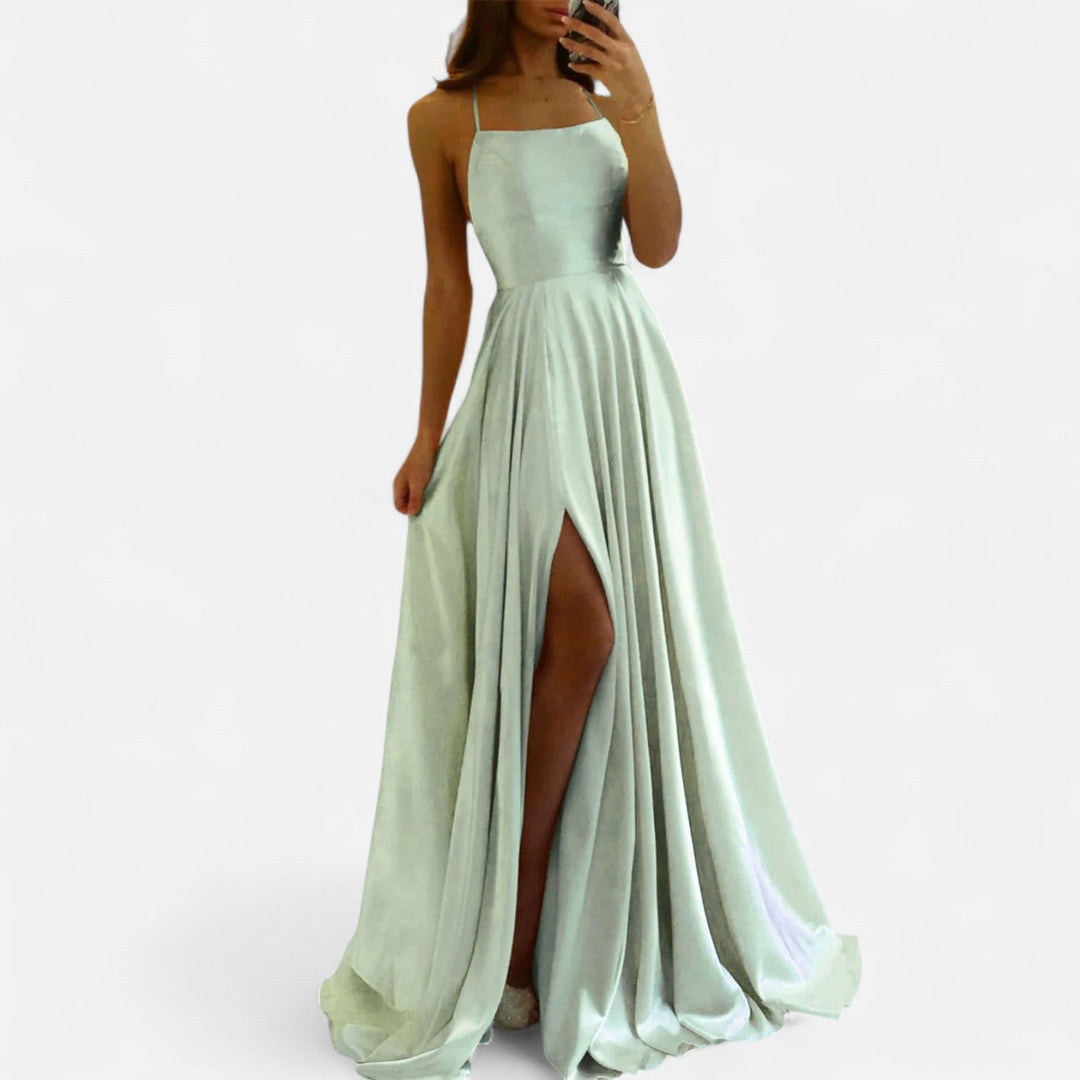 Female model wearing elegant slit maxi dress on plain white background.