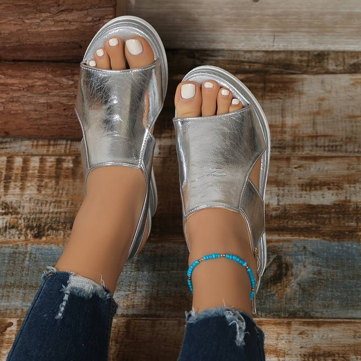 Woman wearing elegant orthopedic sandals with a simple background.