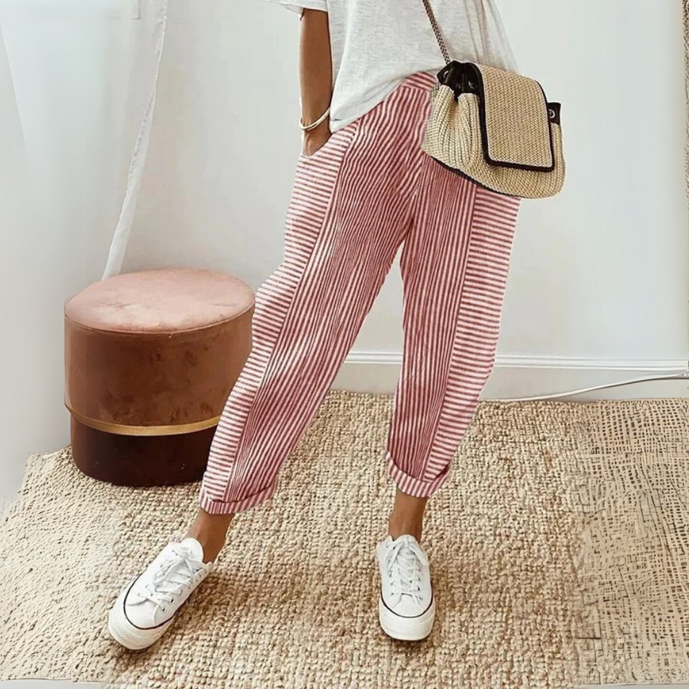 Woman styling striped wide leg pants with a relaxed everyday look on a plain background.