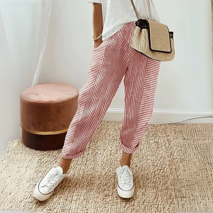Woman styling striped wide leg pants with a relaxed everyday look on a plain background.