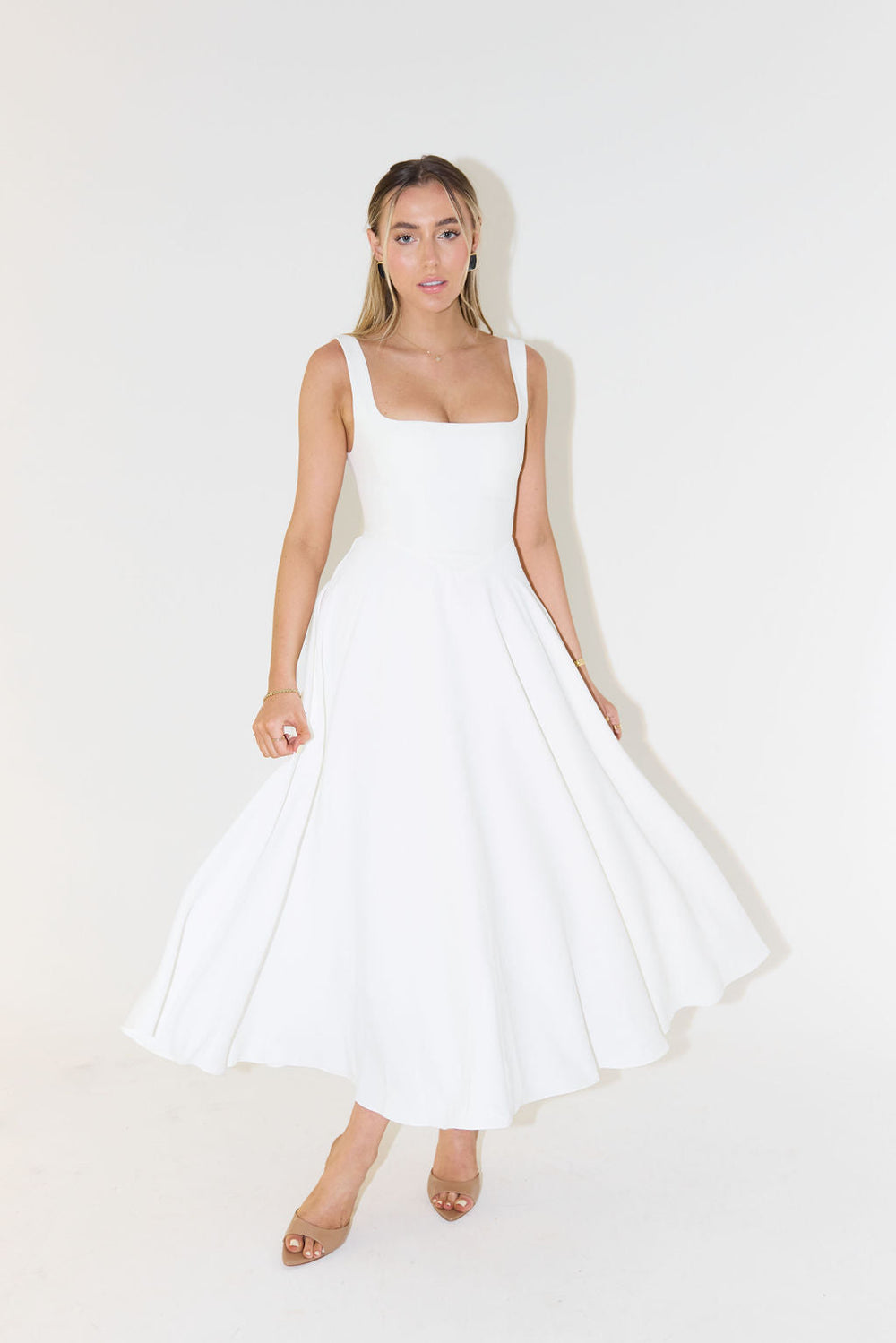 Model in a sleeveless satin midi dress with a fitted bodice on a clean background.