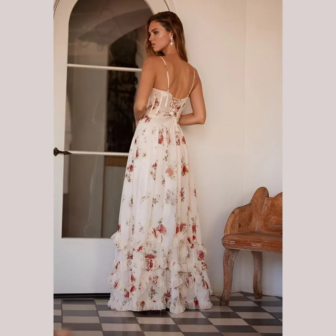 Woman wearing a spaghetti strap floral dress with long flowing skirt on a door glass background.
