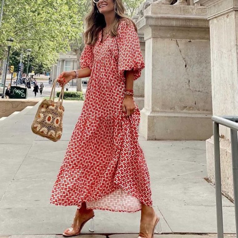 Woman wearing a geometric print maxi dress posing against a plain background.