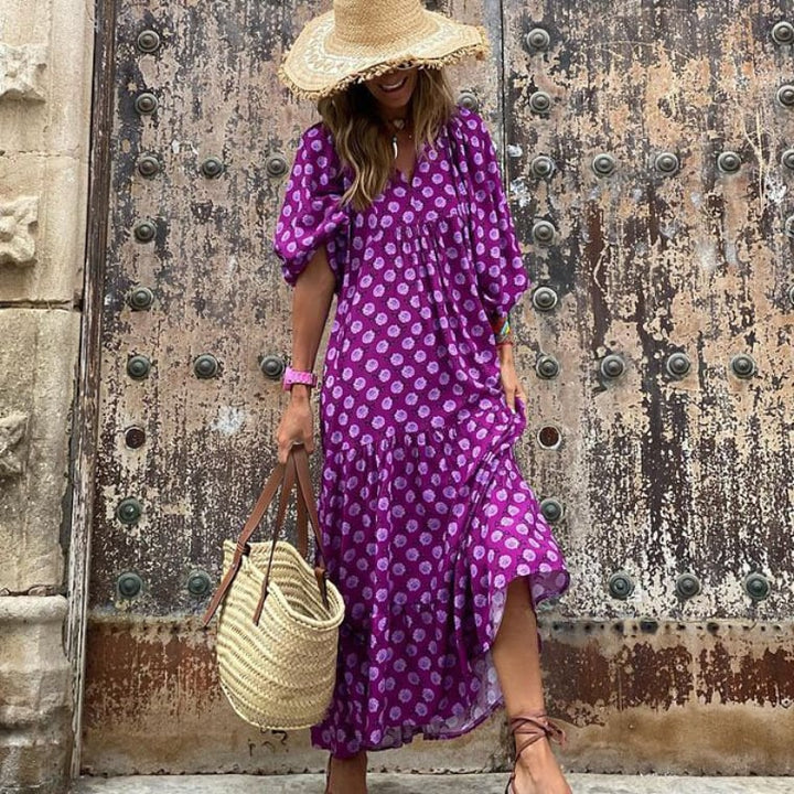 Female model showcasing a flowing boho maxi dress with puff sleeves on a plain backdrop.