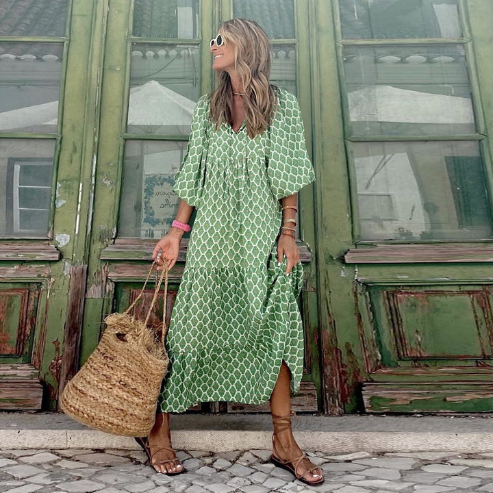 Female wearing a flowing geometric print dress with tie neckline on a plain background.